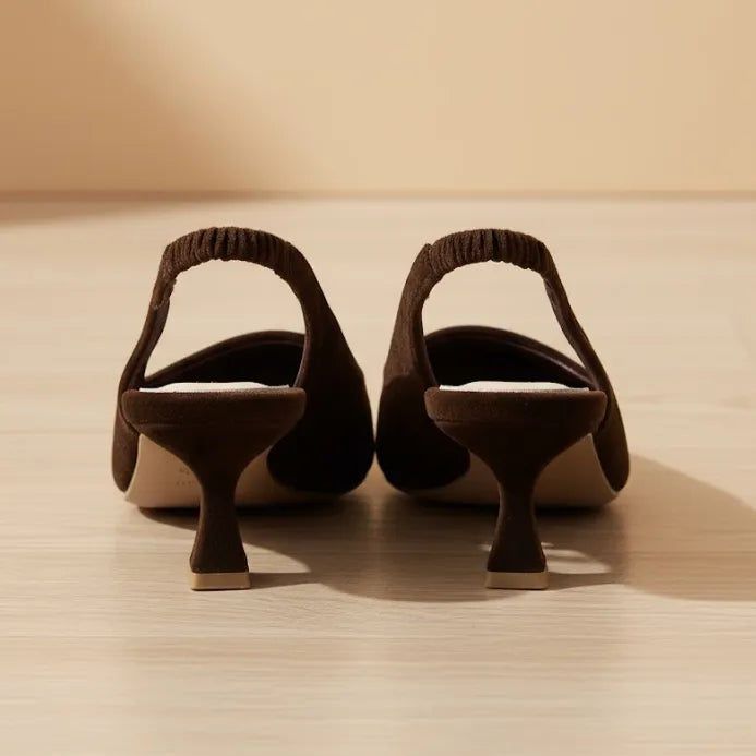 Pair of brown suede shoes with unique heel designs on a wooden surface.
