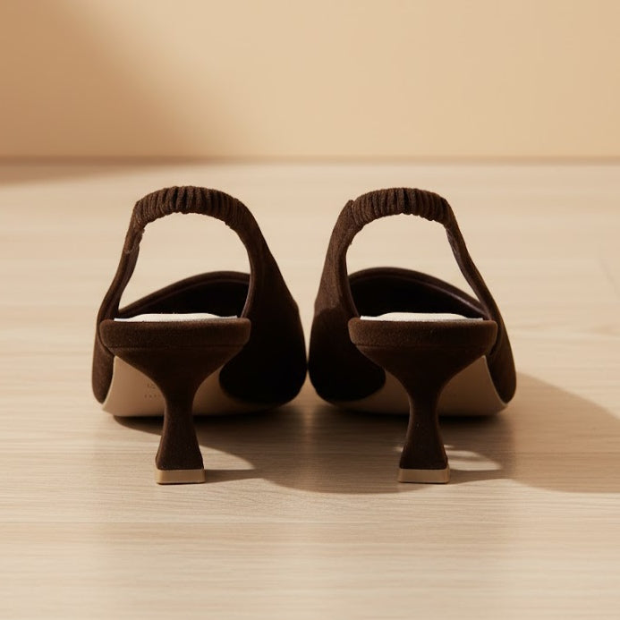 Pair of brown suede shoes with unique heel designs on a wooden surface.