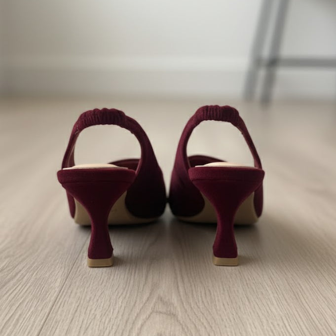 Pair of maroon high-heeled shoes on a wooden floor