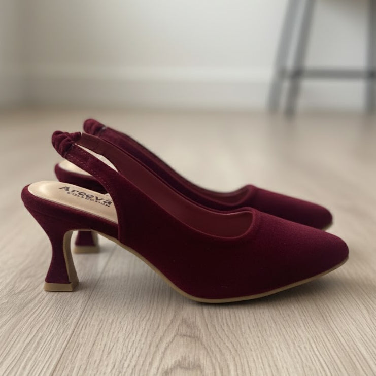Pair of maroon high-heeled shoes on a wooden floor