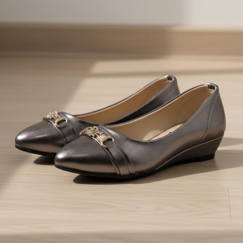 Pair of grey shoes with gold accents on a wooden surface