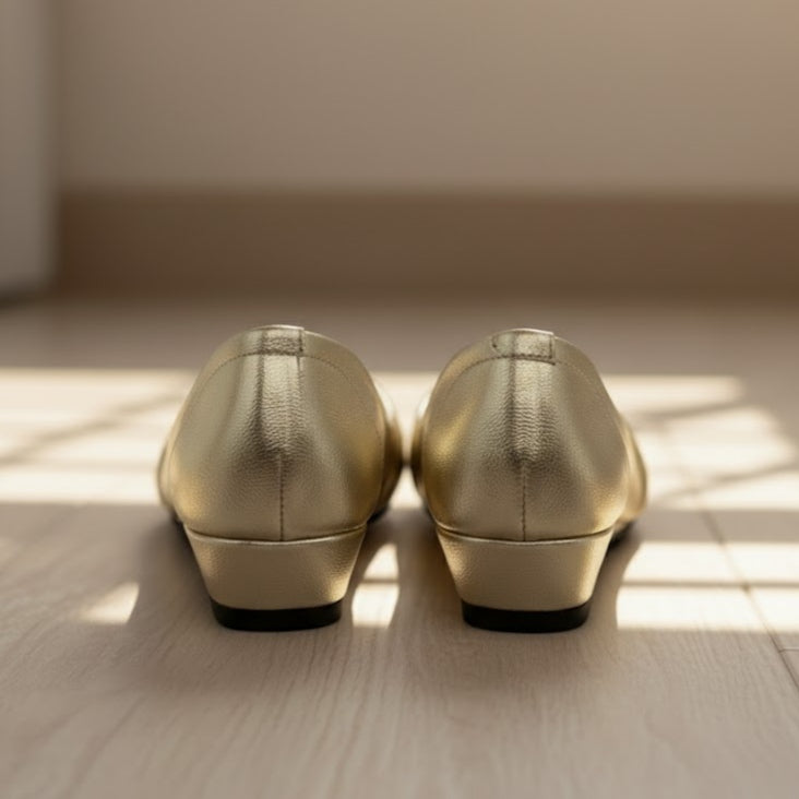 Pair of gold shoes on a wooden floor with soft lighting