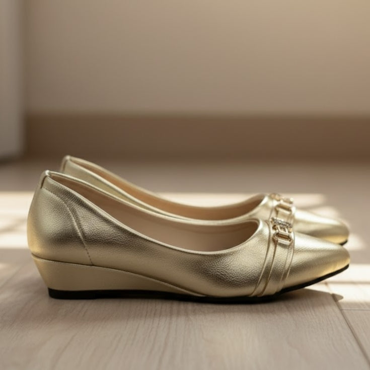 Pair of gold shoes on a wooden surface with a neutral background
