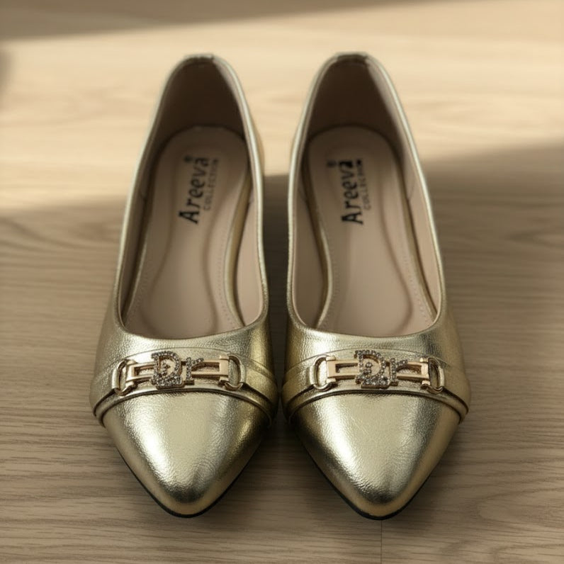 Pair of gold shoes with decorative buckles on a wooden surface
