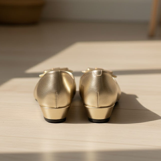Pair of gold shoes on a wooden surface with soft shadows