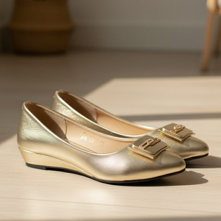 Gold shoes with a decorative buckle on a wooden surface