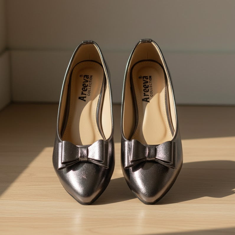 Pair of grey shoes with bow details on a wooden surface