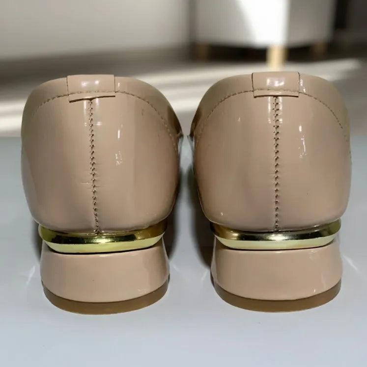 Pair of beige shoes with gold accents on a white surface