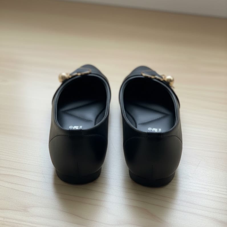 Pair of black shoes with gold accents on a light wooden surface