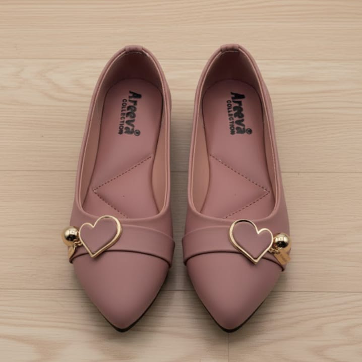 Pair of pink shoes with gold heart designs on a wooden surface