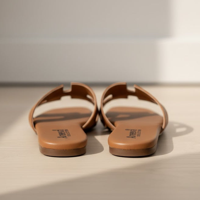 Pair of brown sandals on a light surface with a neutral background