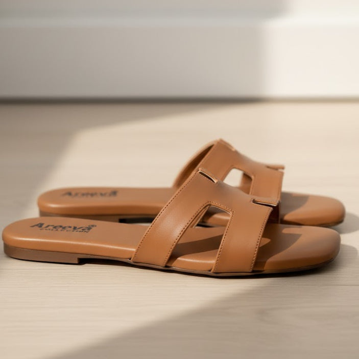 Pair of brown sandals on a light wooden surface