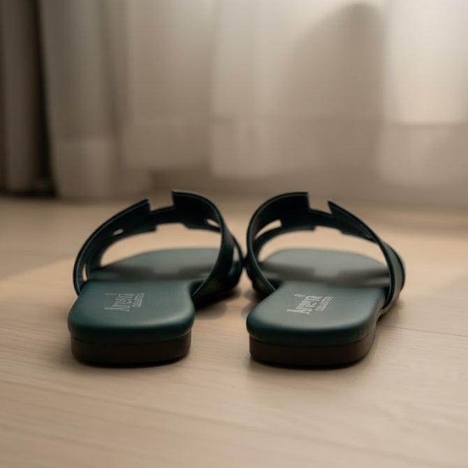 Pair of green sandals on a wooden floor with a blurred background