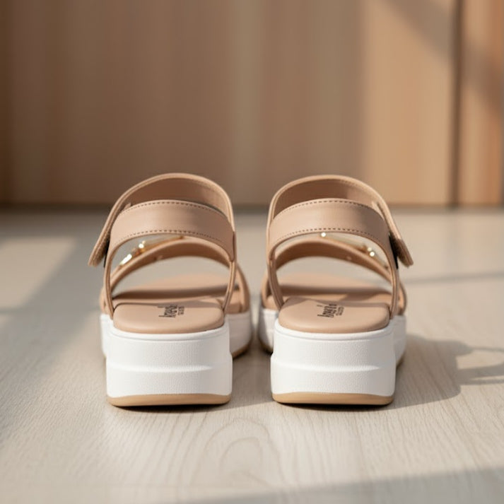 Pair of beige sandals with white soles on a neutral background