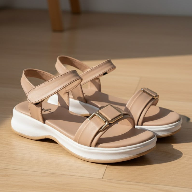 Beige sandals with white soles on a wooden floor