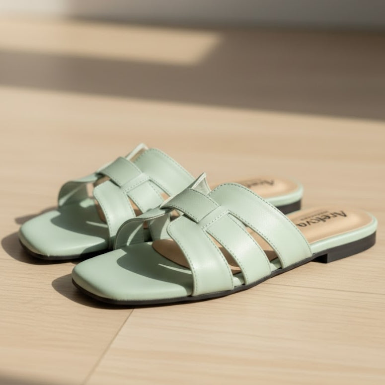 Pair of light green sandals on a beige surface