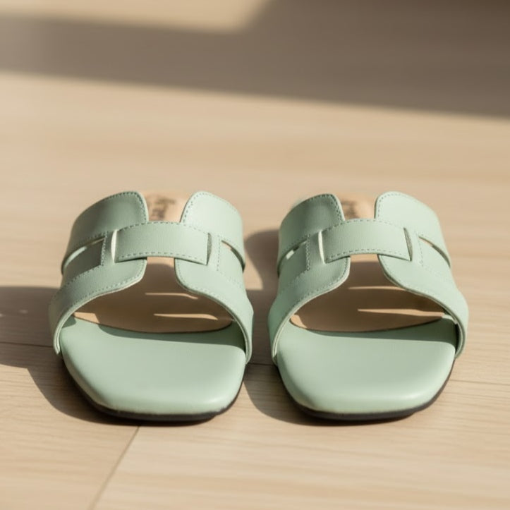 Pair of light green sandals on a beige surface