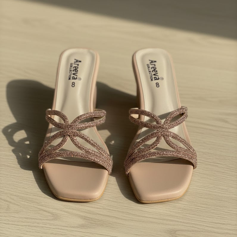Pair of beige high-heeled shoes with decorative straps on a wooden surface