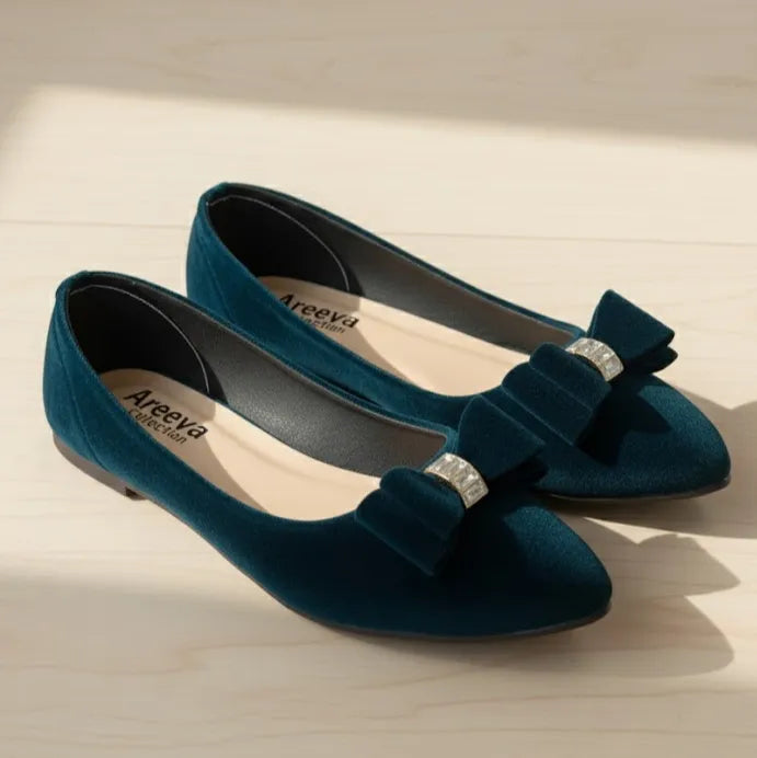 Pair of dark blue shoes with bow details on a light wooden surface