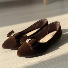 Pair of brown loafers with a bow on a light wooden floor