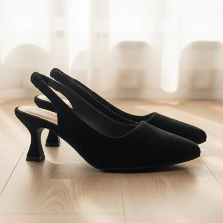 Pair of black high-heeled shoes on a light wooden floor with a blurred background