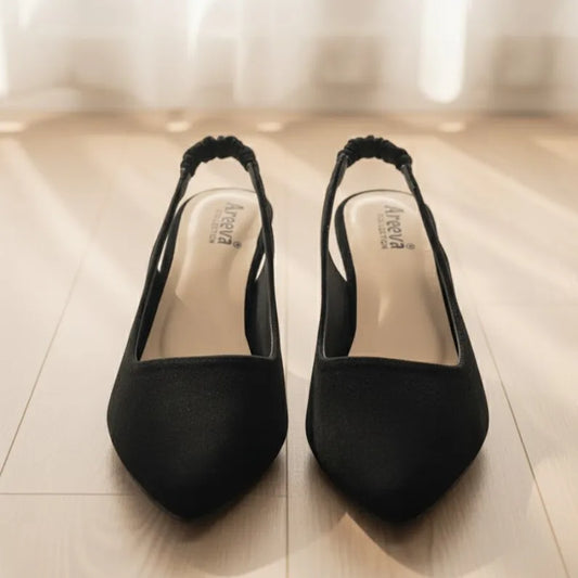 Pair of black high-heeled shoes on a light wooden floor