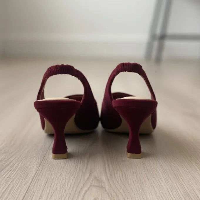 Pair of maroon high-heeled shoes on a wooden floor