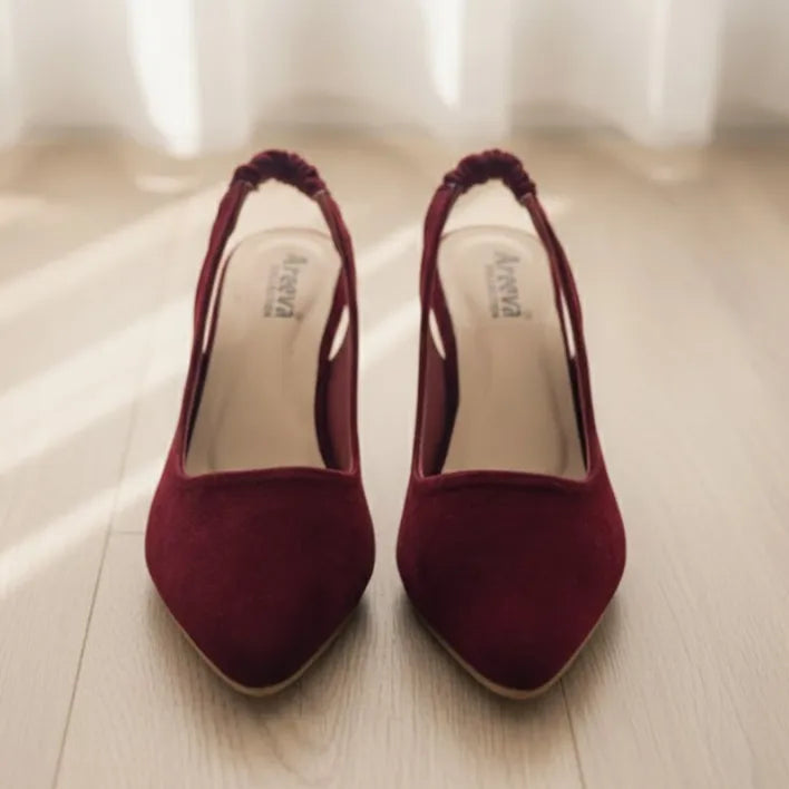 Pair of maroon high-heeled shoes on a light wooden floor.