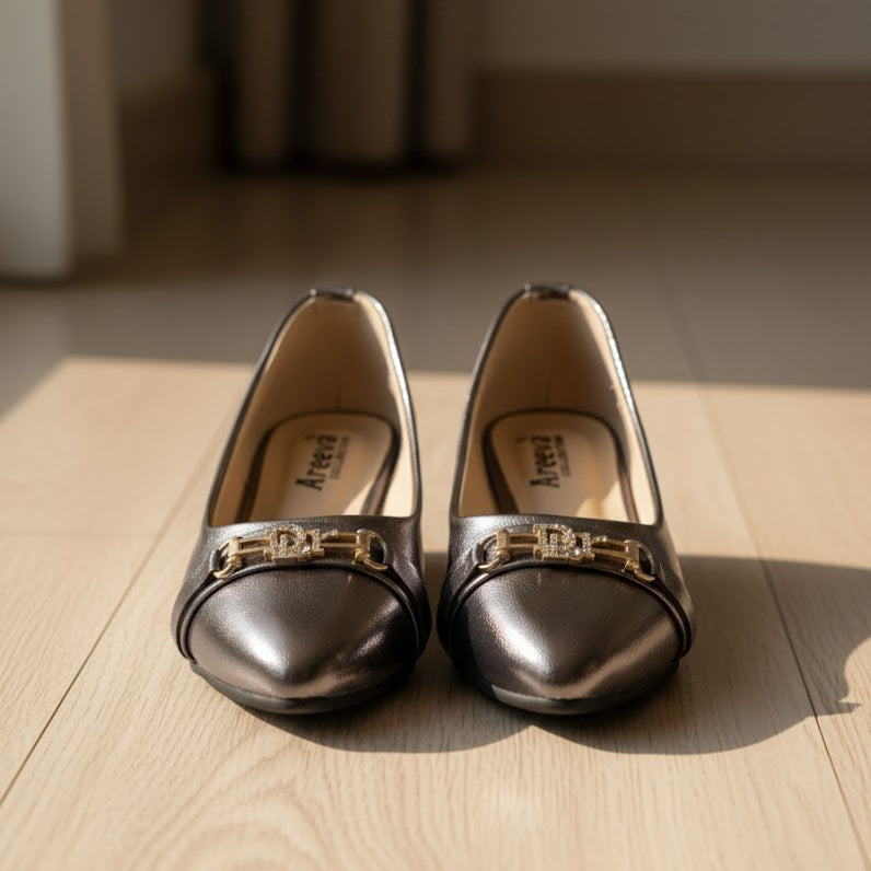 Pair of grey shoes with gold accents on a wooden floor
