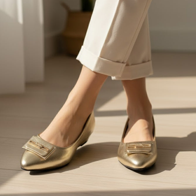 Gold loafers worn with light-colored pants on a neutral background