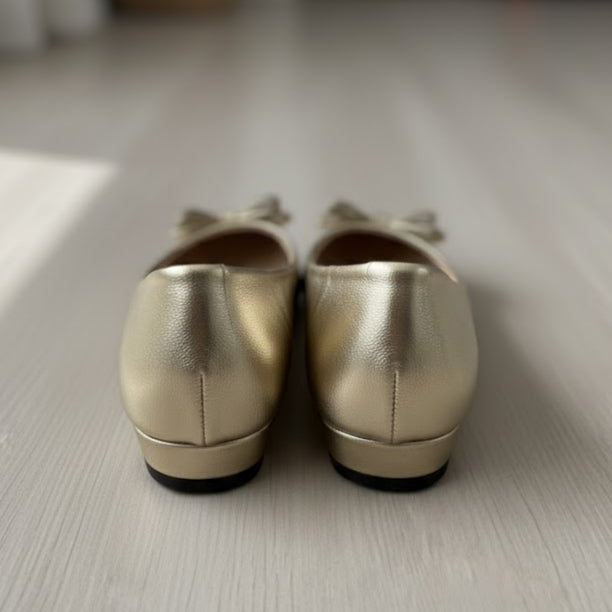 Pair of gold shoes on a light wooden floor