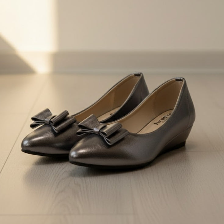 Pair of grey shoes with bows on a light wooden floor