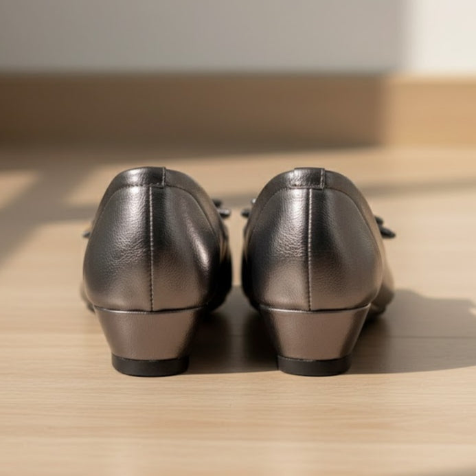 Pair of metallic shoes on a wooden surface with a neutral background