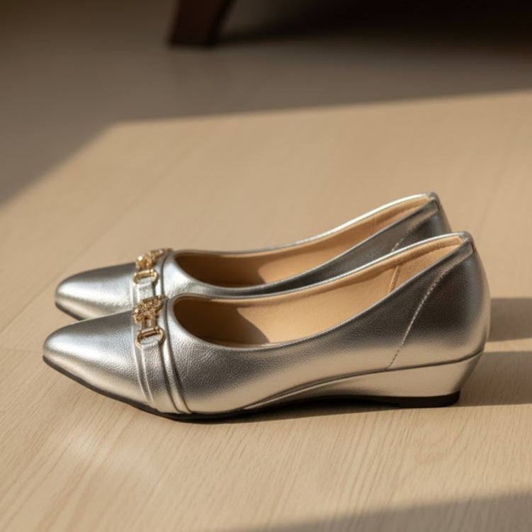 Pair of silver shoes with gold accents on a wooden surface