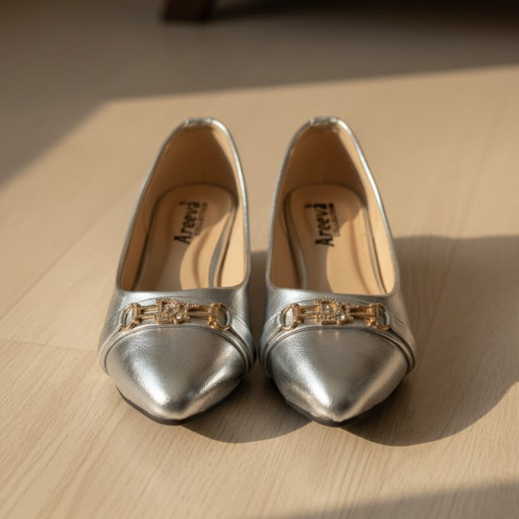 Pair of silver shoes with gold accents on a wooden surface