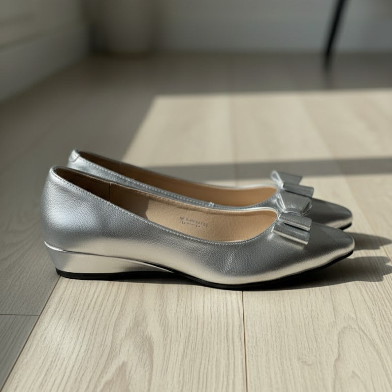 Silver shoes with a bow on a wooden floor