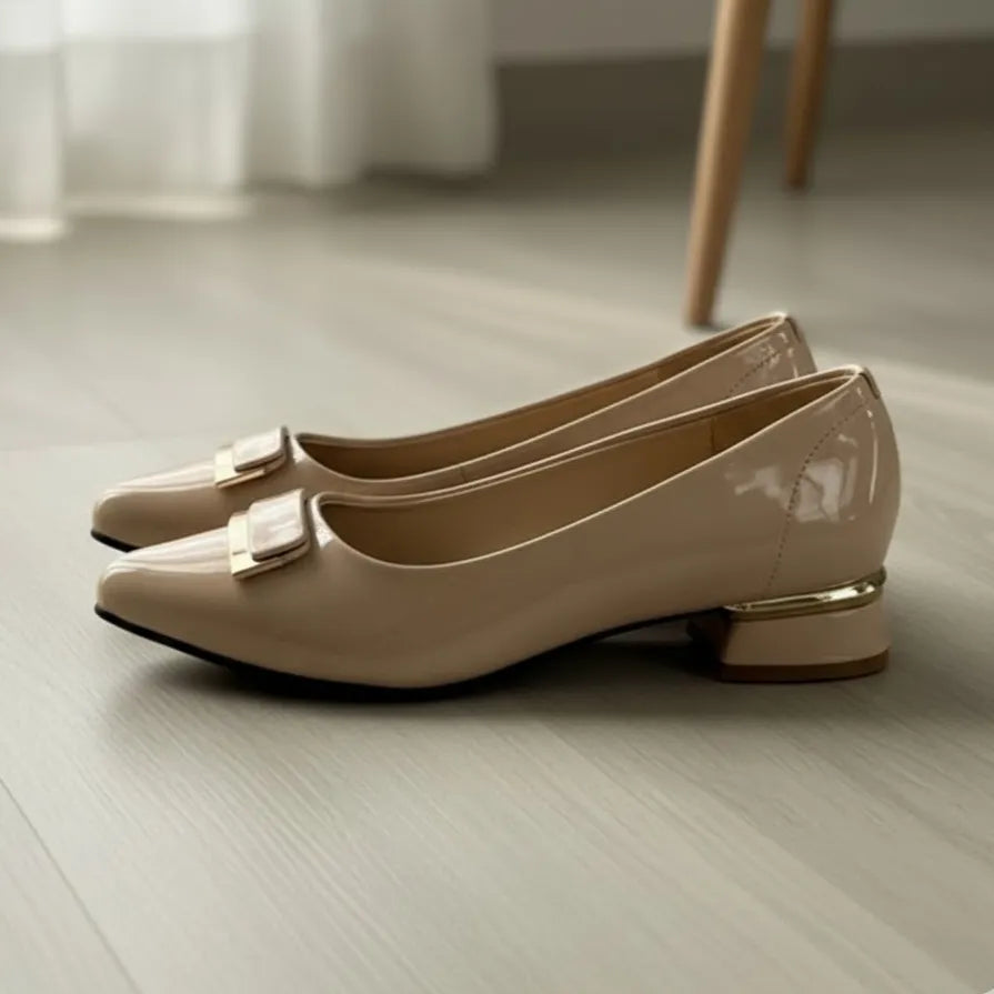 Pair of beige shoes with gold accents on a light wooden floor.
