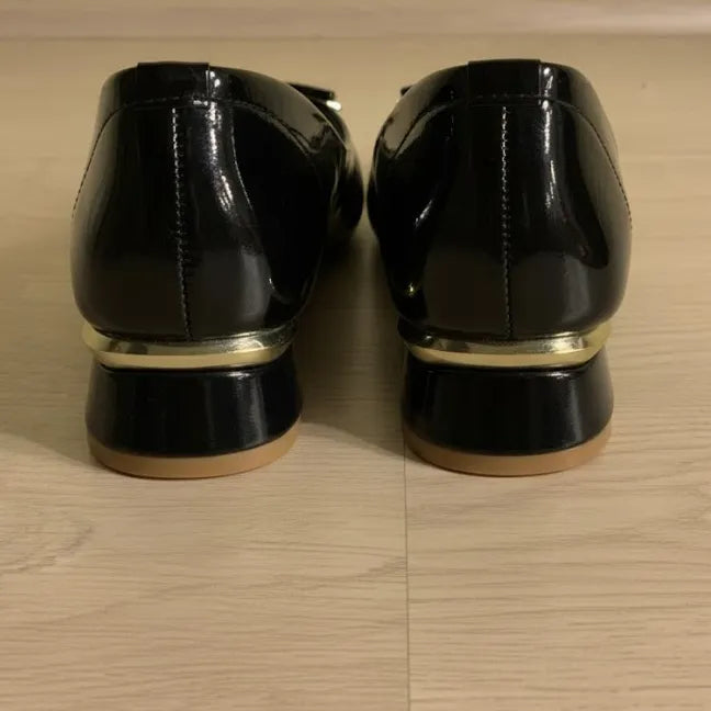 Pair of black patent leather shoes on a wooden floor