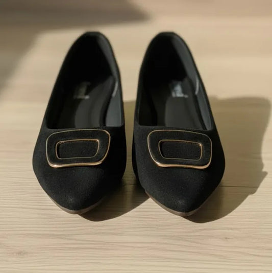 Pair of black loafers with gold accents on a wooden surface