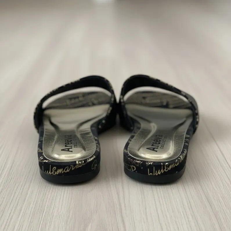 Pair of black slippers with white soles on a light wooden floor