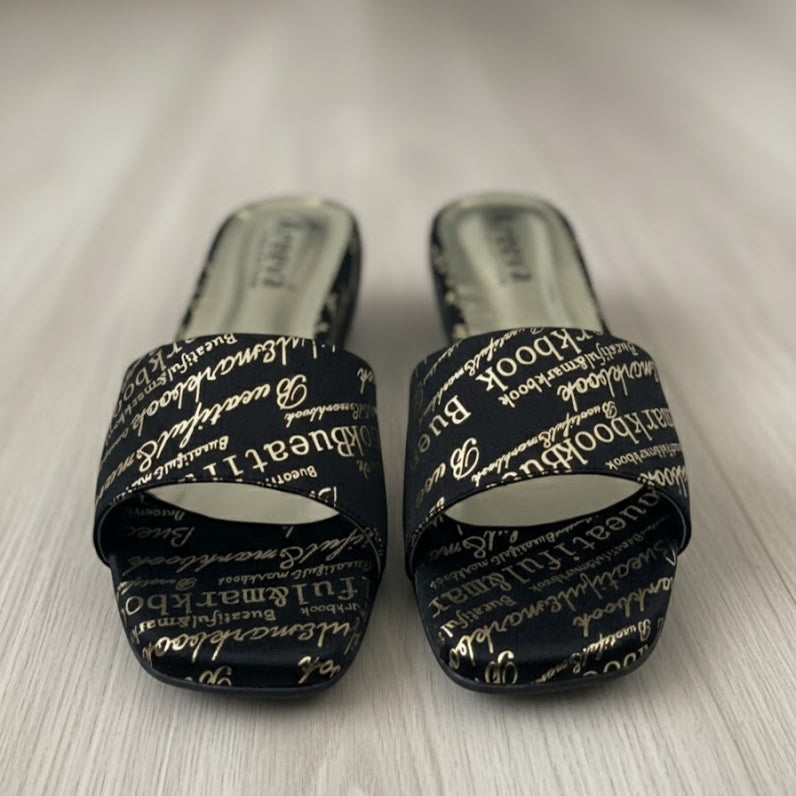 Pair of black slides with white text on a light wooden floor