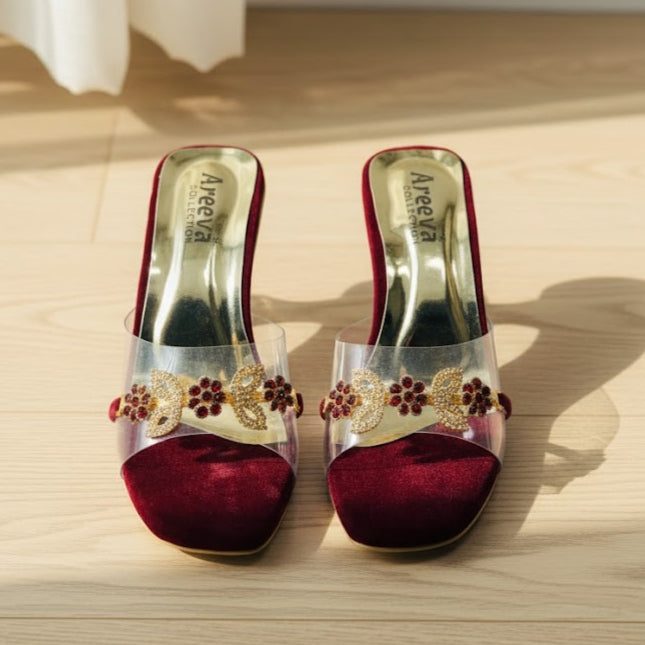 Red velvet sandals with clear straps and floral embellishments on a wooden surface
