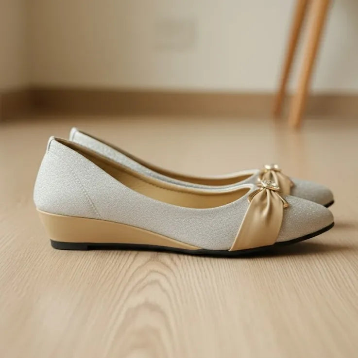 Pair of beige shoes with a bow on a wooden floor