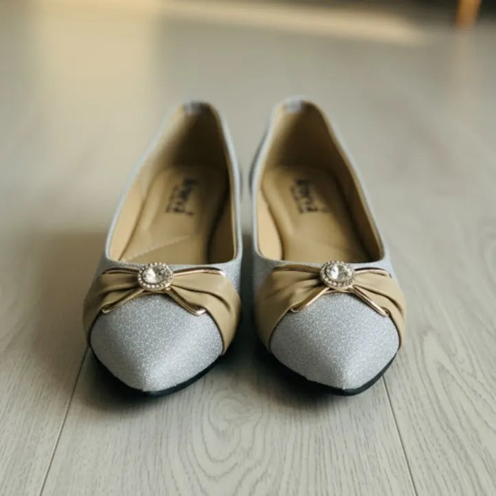 Pair of decorative shoes with bow and gemstone on a wooden floor