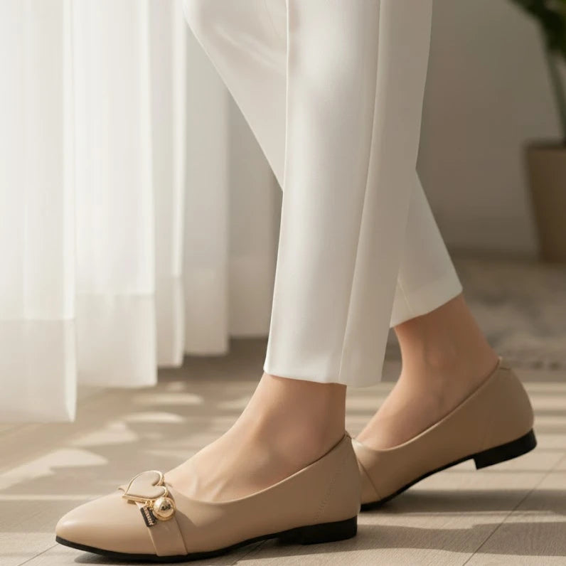 Beige loafers worn with white pants on a neutral background