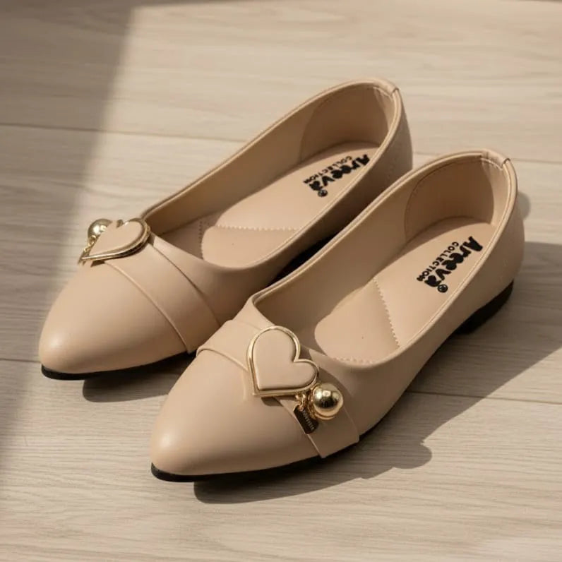 Pair of beige shoes with heart-shaped embellishments on a wooden surface