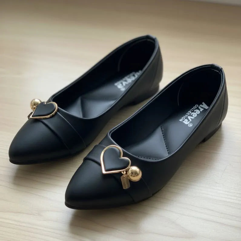 Black shoes with heart-shaped gold charms on a light wooden surface