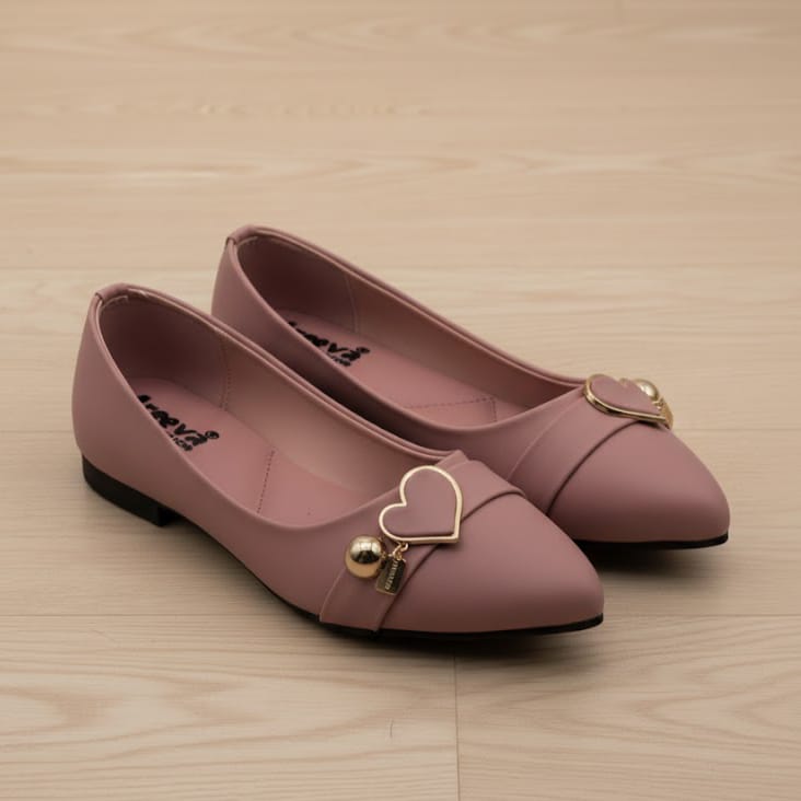 Pair of pink shoes with heart-shaped embellishments on a wooden surface