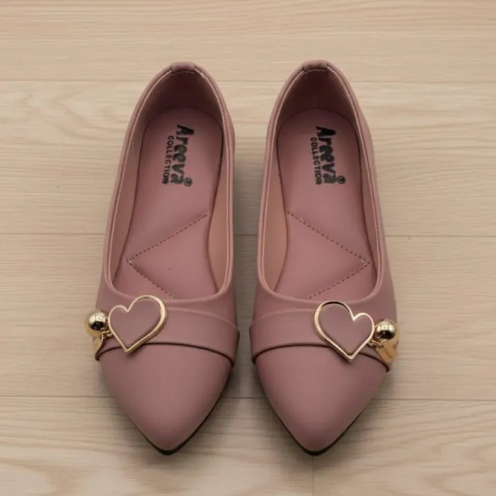Pair of pink shoes with gold heart details on a wooden surface