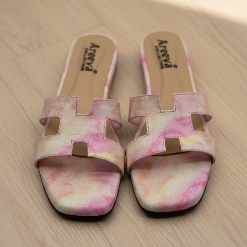Pair of pink and white patterned sandals on a wooden surface